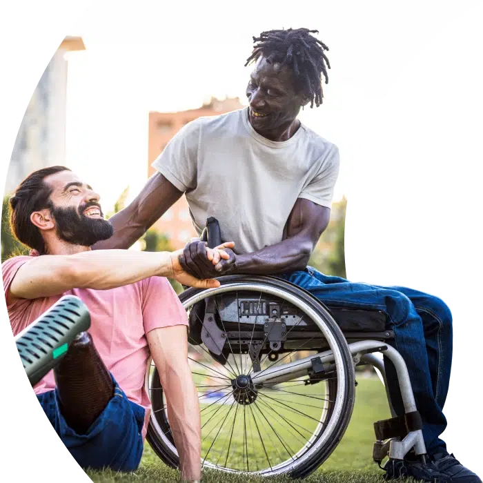 Two men with disabilities laughing and supporting each other outdoors